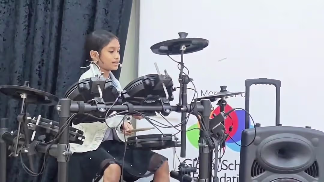 Student playing drums on stage at a school event | Regent International School