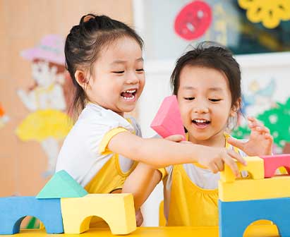 Kids playing outdoors, showcasing the Cambridge Early Years Foundation Curriculum